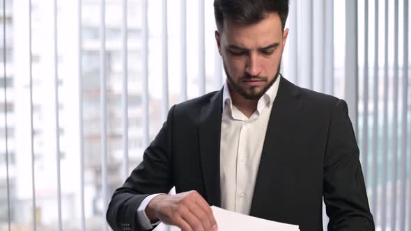 The camera zooms in on the face of a young manager, who is examining papers alt