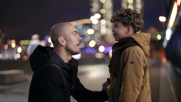 Portrait in Profile of a Father and Son in a Blurry Evening Street alt