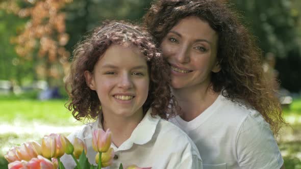 Portrait of a Woman Hugging Her Teenage Daughter with a Bouquet of Tulips