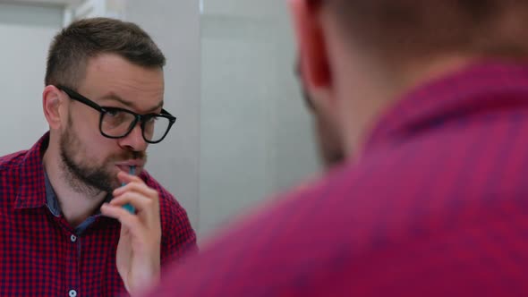 Bearded Man Brushing His Teeth in a Bathroom in the Morning alt