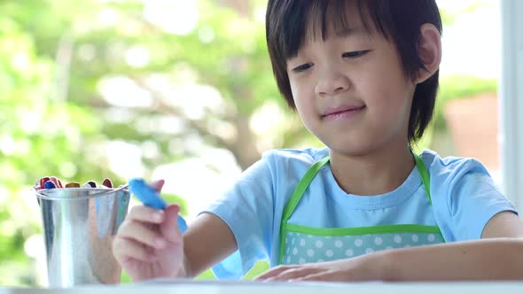 Cute Asian Child Drawing With Crayons On White Table alt
