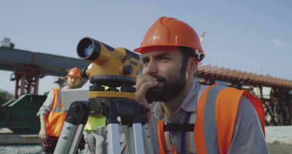 Male Surveyors Using Theodolite Together alt