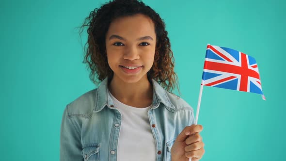 Slow Motion of Pretty Mixed Race Woman Holding Flag of England Smiling alt