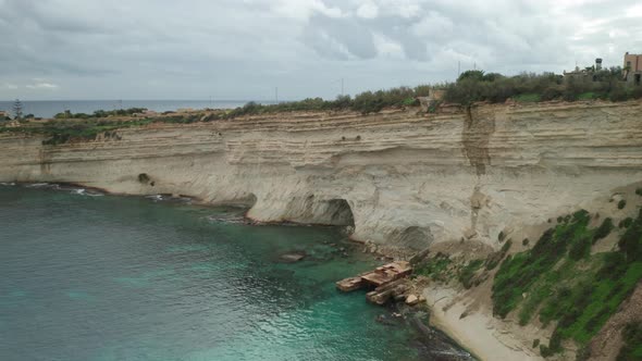 AERIAL: Ta Kalanka Sea Cave Coastline with Turquoise Color Water in Il-Hofra l-Kbira Bay