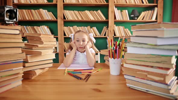 Tired Teenage Girl in the Library Falls From Fatigue on the Table with Books alt