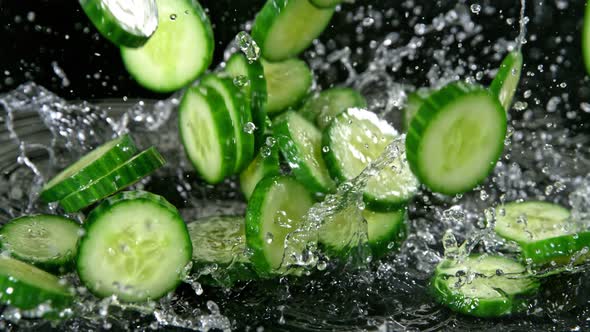 Super Slow Motion Shot of Cucumber Slices Falling Into Water on Black Background at 1000Fps alt