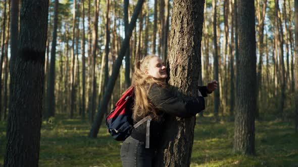 Girl Hugging a Pine Tree and Smiling alt
