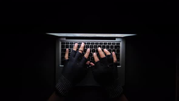 Hacker Hand Stealing Data From Laptop Top Down alt