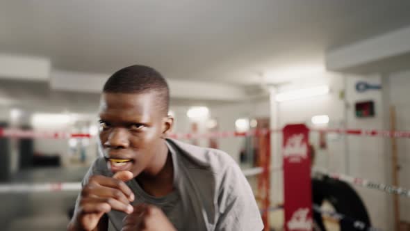 Young Motivated African Sportsman Boxer Throwing Punches at Camera During Boxing Training in Gym alt