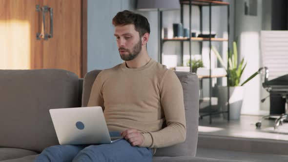 Young man experiencing stress at work with laptop at home alt