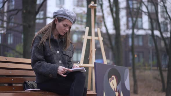 Concentrated Skilled Woman Drawing Sketch with Picture at Easel at Background alt