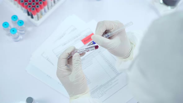 Doctor or Scientist checking sampling blood tube to make a medical diagnosis.