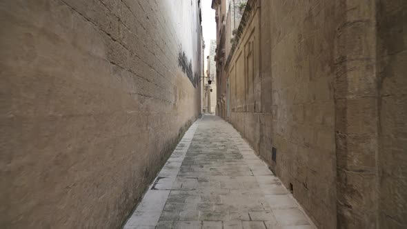 Very Narrow Old Street with Cobblestone Path and Tall Walls in Mdina, Malta