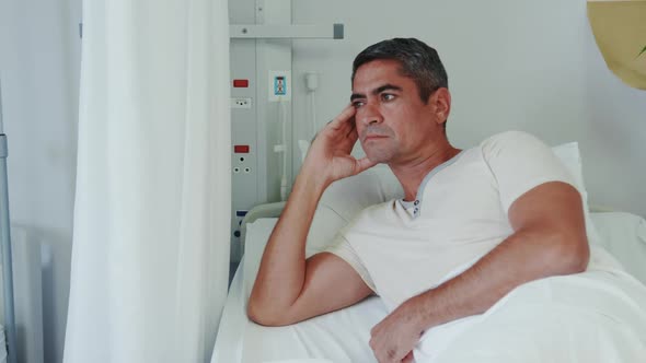 Front view of Caucasian male patient looking away while lying on hospital bed in hospital ward 4k alt