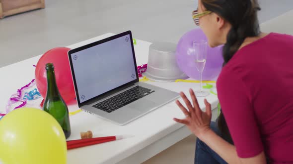 Happy asian woman with champagne making new year's eve video call on laptop with copy space alt