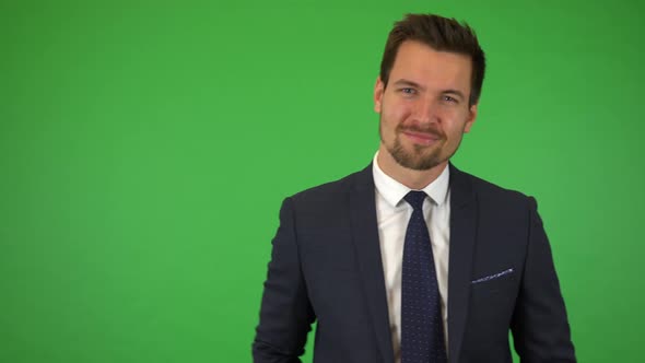 A Young Handsome Businessman Points at the Camera and Nods with a Smile - Green Screen Studio alt