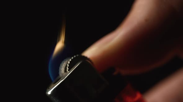 Extreme Close Up Shot of Man Hand Igniting Lighter Against Black Background