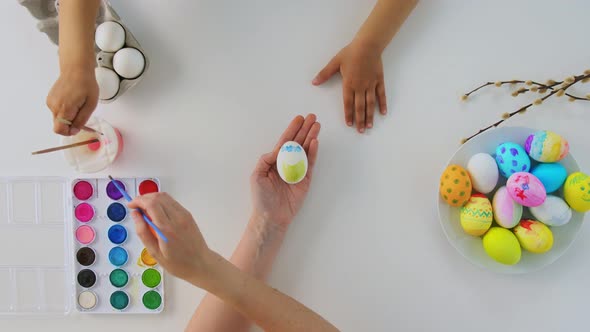 Hands of Child and Parent Coloring Easter Eggs