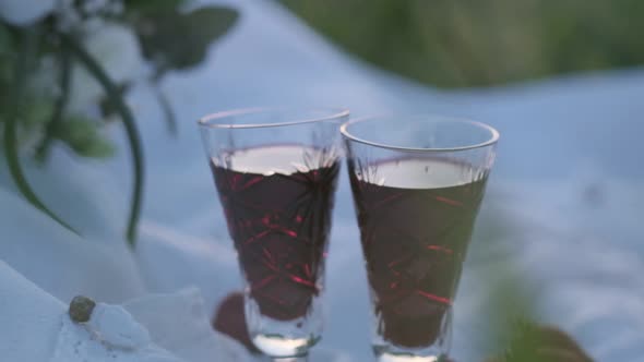 Two Wedding Crystal Glasses with Red Wine on the Background of a Bouquet of White Roses with alt