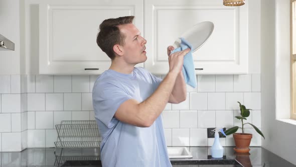 Attractive Young Caucasian Man Washing Dishes at Kitchen Sink While Doing Cleaning at Home at