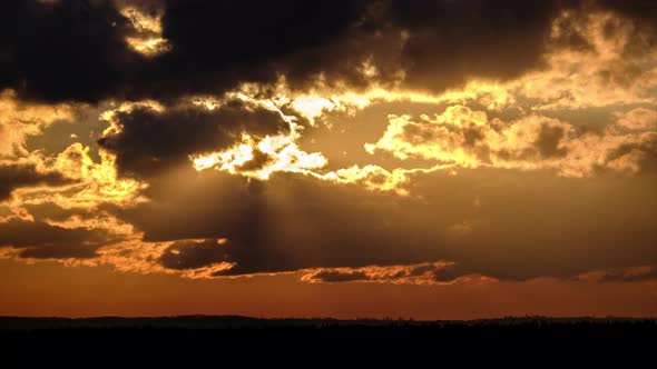 Dramatic Sunset with Sun Rays in Sky Through Orange Layered Clouds Timelapse alt