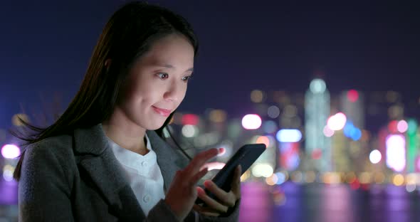 Businesswoman use of cellphone in city at night alt