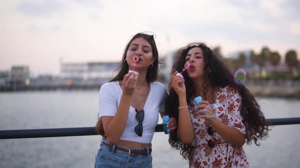 Young Hipster Women Having Fun Blowing Bubbles By the Sea