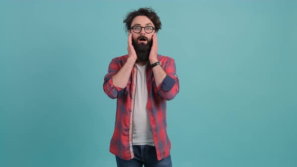 Young Bearded Man Showing Surprise and Amazed Expression with Hands on Face alt