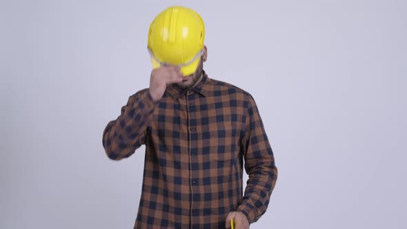 Happy Young Bearded Indian Man Construction Worker Giving Hardhat alt