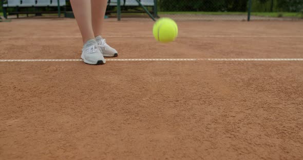Low Angle Crop View of Tennis Player Bouncing the Ball Raising It From Clay Court Slow Motion