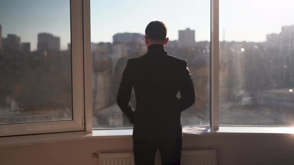 Contemplative Businessman Looking at the City Through a Large Window Thoughtful Entrepreneur alt