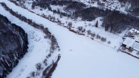 Aerial flying high on frozen wintery river in snow