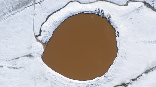 Aerial top down rotation of a crater lake Birkat Ram, in snow on Mount Hermon, Israel, The mountain alt