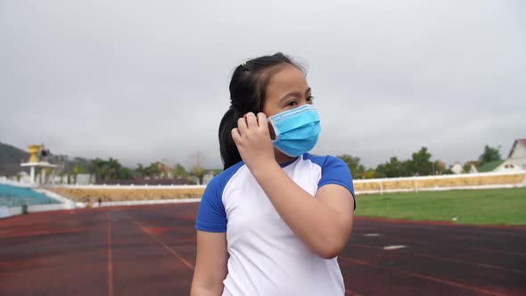 Little Girl Takes Off The Medical Flu Mask At Stadium alt