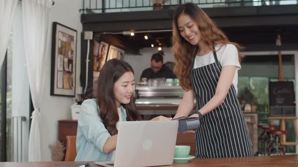 asian freelance women pay contactless credit card at coffee shop. Asian happy girl barista.. alt