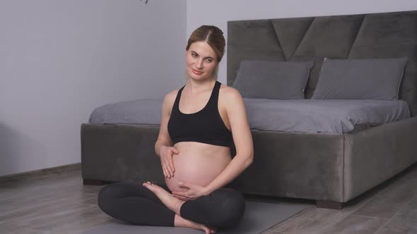 Woman Expecting a Baby Holds Her Hands on Her Stomach Meditates on the Floor of the House Enjoying