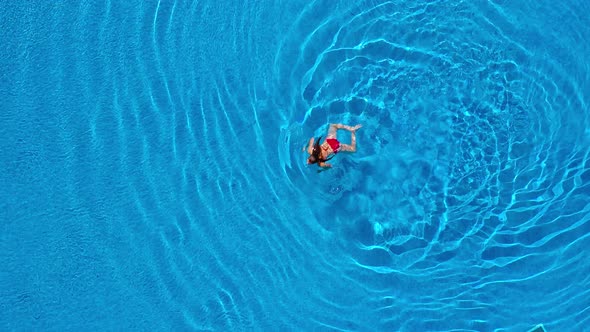 View From the Top As a Woman in Red Swimsuit Swims in the Pool alt