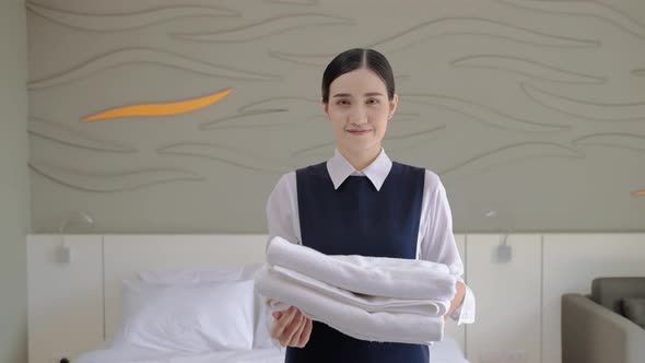 Portrait, the maid is standing smiling, holding a towel.