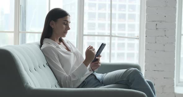 Relaxed Woman Using Mobile Phone Applications Communicating in Social Network or Shopping Online alt