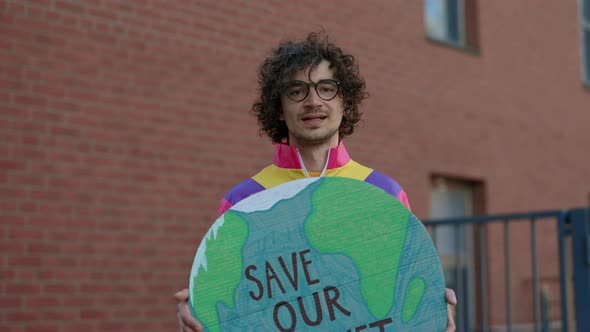 Male Activist Posing on Street with Save Our Planet Banner alt