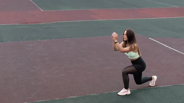 Fit Athleti Woman Is Training Doing Lunges on Sport Stadium Ground in Campus.