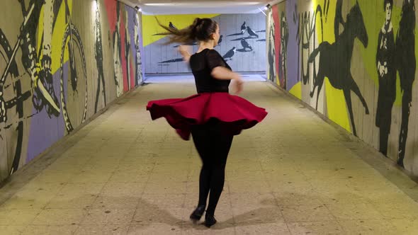 Beautiful dancer practices dancing in graffiti covered passage alt
