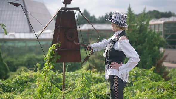 Slim Woman in Steampunk Outfit Aiming and Shooting in Slow Motion Standing Outdoors alt