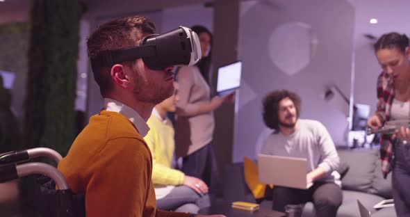 Disabled Businessman in a Wheelchair at Work in Modern Open Space Coworking Office on Team Meeting alt