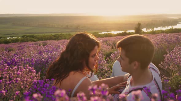 A Happy Couple of People in Love Have Fun Jostling Sitting in a Lavender Field