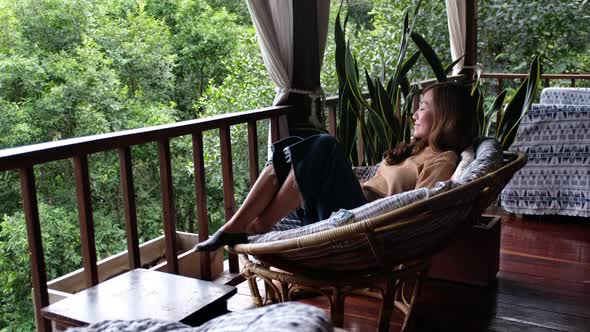 A young asian woman lying in sofa on balcony and looking at nature view