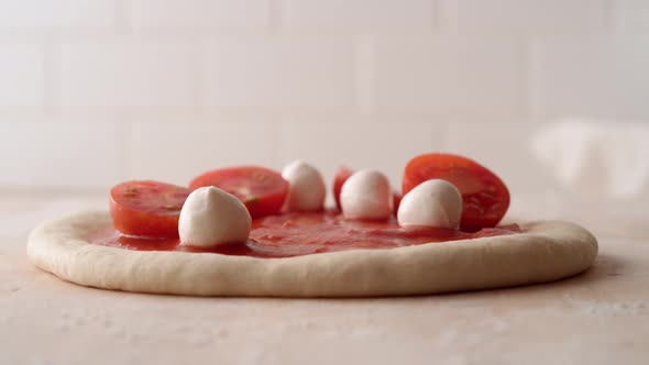 Camera follows putting tomato and mozzarella cheese on a pizza dough. Slow Motion. alt