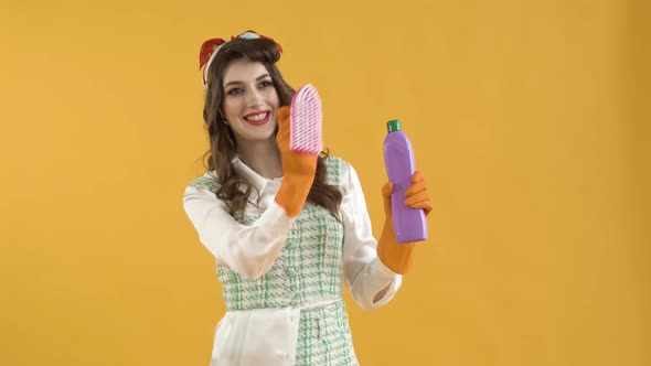 A Young Woman Moves a Brush in the Air and Holds a Bottle of Household Chemicals