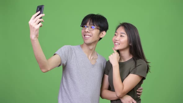 Young Asian Couple Using Phone Together