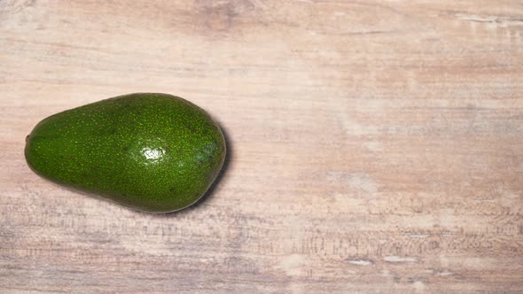 The Avocado Turns Around Itself on a Wooden Table, Stop Motion Animation. Healthy Vegetarian Food